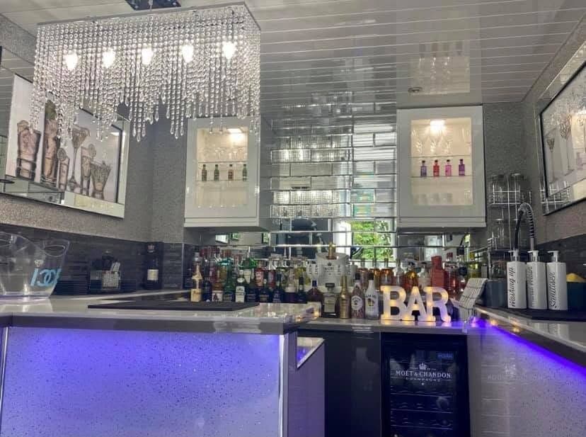 Bar fit-out with crystal chandeliers over the counter and colour-changing LED lighting to the bar front